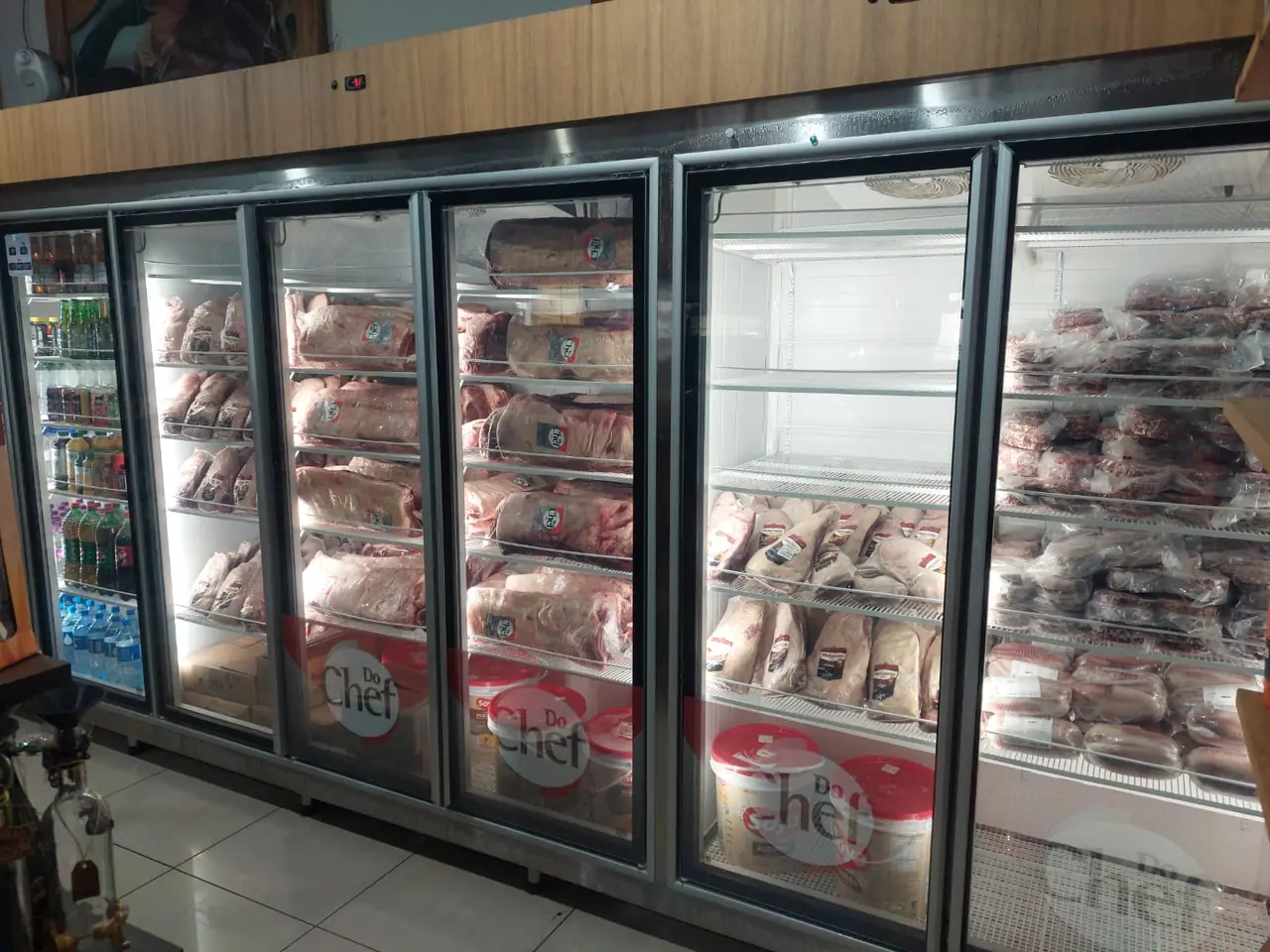 Câmara expositora com portas de vidro exibindo cortes de carne resfriada em açougue